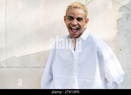 Porträt eines schönen modernen jungen schwarzen Mannes mit blonden Haaren, der die Kamera lächelnd und lustig sieht Stockfoto