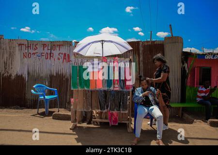 Eine Frau bekommt ihre Haare vor den Straßen in Kibera Slum, Nairobi. Ein Blick durch den Alltag in Kibera, dem derzeit größten Slum Afrikas Stockfoto