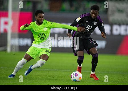 Wolfsburg, Deutschland. Dezember 2023. Fußball: Bundesliga, VfL Wolfsburg - Bayern München, Spieltag 16, Volkswagen Arena. Wolfsburgs Ridle Baku (l) spielt gegen den Münchner Alphonso Davies. Hinweis: Swen Pförtner/dpa – WICHTIGER HINWEIS: gemäß den Vorschriften der DFL Deutscher Fußball-Liga und des DFB Deutscher Fußball-Bundes ist es verboten, im Stadion und/oder des Spiels aufgenommene Fotografien in Form von sequenziellen Bildern und/oder videoähnlichen Fotoserien zu verwenden oder zu nutzen./dpa/Alamy Live News Stockfoto