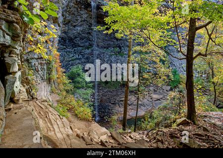 Sie stehen am Felsvorsprung neben der Schluchtwand mit Blick auf den kargen Wasserfall, der über den Rand hinunter zum flachen Pool unter einer hellen sonne fließt Stockfoto