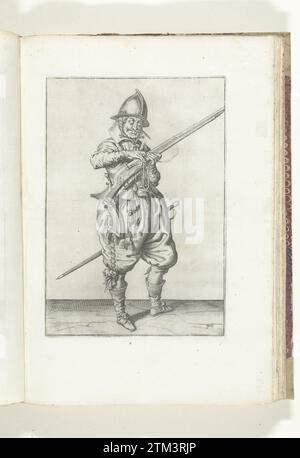 Soldat auf der Wache drückt seinen Docht auf den Hahn seines Ruders (Nr. 40), ca. 1600, 1608 Ein Wachsoldat, rechts, rechts, der mit der linken Hand (Nr. 40) ein Ruder (eine bestimmte Schusswaffe) hält, ca. 1600. Mit der rechten Hand drückt er einen brennenden Docht auf den Hahn (Teil des Entzündungsmechanismus) seines Ruders. Es handelt sich also um die gleiche Position wie die, die auf dem siebten Druck der Serie zu sehen ist. Schild 40 in der Anleitung zur Handhabung des Ruders. Teil der Illustrationen in: J. de Gheyn, Waffenhandel von Roers Musquetten and Spiessen, Amsterdam, 1608. W Stockfoto