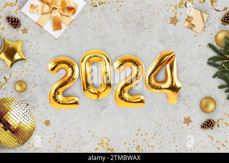 Silvester Golden Balls 2024 Luxus auf Einem grauen Betontisch mit Geschenken, Golden Disco Ball, Weihnachtsbaumzweige und Konfetti, Top View. Neujahr 202 Stockfoto