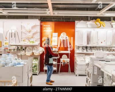 Paris, Frankreich - 31. August 2023: Eine einsame Frau blickt auf einen Kinderstuhl in einem IKEA-Geschäft und reflektiert einen Moment der Besinnung inmitten der geschäftigen Schweden Stockfoto