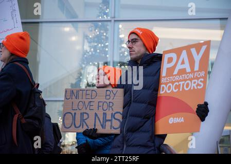 London, Großbritannien. Dezember 2023. Ein Demonstrant hält Plakate vor dem University College Hospital in London, Großbritannien. BMA (British Medical Association) sagt, dass die Bezahlung der Ärzte in der Nachwuchsärzte seit 2008 um mehr als ein Viertel gekürzt wurde. Aus diesem Grund streiken sie für eine vollständige Lohnwiederherstellung. (Foto: Krisztian Elek/SOPA Images/SIPA USA) Credit: SIPA USA/Alamy Live News Stockfoto