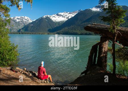 Ein ruhiger Moment am Cheakamus Lake, während ein Individuum Trost durch das Gletscherwasser findet, umgeben von der unberührten Wildnis von British Columbia. Stockfoto