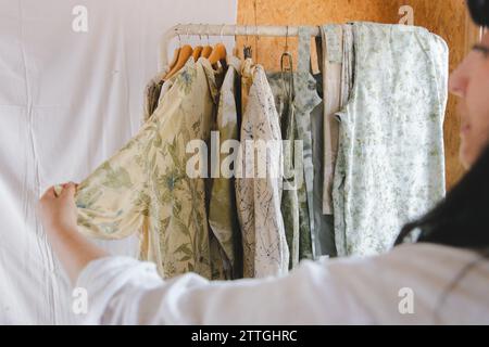 Textilkünstler hält ein Hemd mit Naturblumenfarbe drauf. Umweltfreundlicher botanischer Aufdruck auf der Garderobe für Faserbekleidung. Stockfoto