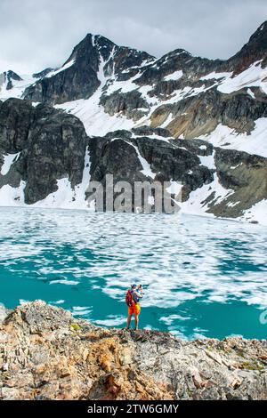 Ein einsamer Wanderer betrachtet die Weite des eisigen Wedgemount Lake. Stockfoto