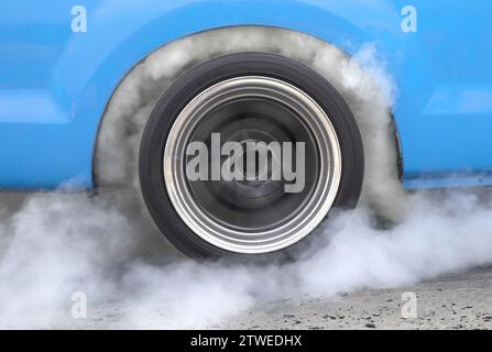 Ziehen Sie den brennenden Reifen des Rennwagens an der Startlinie auf der Rennstrecke Stockfoto