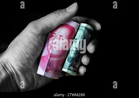 US-Dollar und chinesischer Yuan in der Hand isoliert auf schwarzem Hintergrund Stockfoto