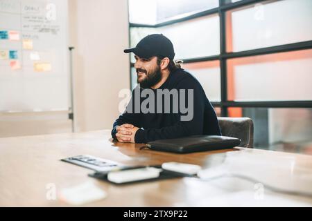 Ein junger Unternehmer führt mit seinem professionellen Team in einem Sitzungssaal ein kreatives Gespräch. Dieser fröhliche, lächelnde Geschäftsmann zeigt sein d Stockfoto