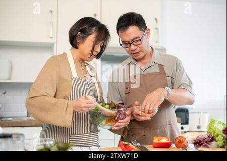 Ein fürsorglicher asiatischer Ehemann hilft seiner Frau, in der Küche zu frühstücken, und verbringt gemeinsam zu Hause gute Zeit. Schönes erwachsenes Paar, Hausmannskost, Stockfoto