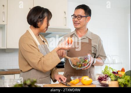 Ein fürsorglicher asiatischer Ehemann hilft seiner Frau, in der Küche zu frühstücken, und verbringt gemeinsam zu Hause gute Zeit. Schönes erwachsenes Paar, Hausmannskost, Stockfoto