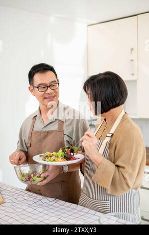 Ein hübsches asiatisches Paar genießt das Essen nach dem Kochen in der Küche und verbringt am Wochenende eine gute Zeit zu Hause. Erwachsene Paare Stockfoto