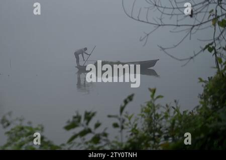 Ein Arbeiter sammelt Plankton an einem nebeligen Morgen am MBB College Lake in Agartala. Tripura, Indien. Stockfoto