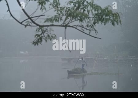 Ein Arbeiter sammelt Plankton an einem nebeligen Morgen am MBB College Lake in Agartala. Tripura, Indien. Stockfoto