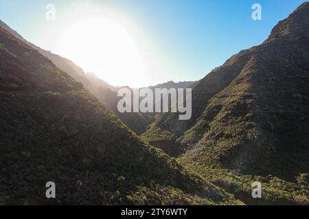 Atemberaubende horizontale Aufnahme fängt den ruhigen Moment des Sonnenaufgangs über einer zerklüfteten Bergkette ein. Die steilen Hänge, bedeckt mit grüner Vegetation, sind Stockfoto