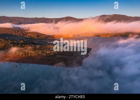 Blick aus der Vogelperspektive auf das goldene Morgenlicht über einem nebelbedeckten See am Lake Eildon im High Country von Victoria, Australien. Stockfoto