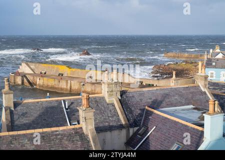 Findochty Harbour und Häuserdächer entlang der Küste mit einem turbulenten Meer. Findochty, Morayshire, Schottland Stockfoto