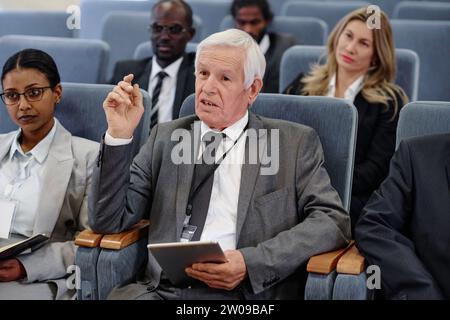 Reifer Geschäftsmann, der Tablet-pc nutzt und während einer Geschäftskonferenz spricht Stockfoto