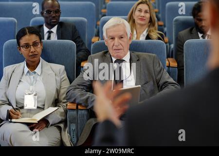 Gruppe von Geschäftsleuten, die den Rednern zuhören, während sie auf einer Geschäftskonferenz sitzen Stockfoto