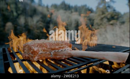 Steakgrillen am Feuer. Mit Rosmarin auffüllen, um das köstliche Fleisch hinzuzufügen. Stockfoto