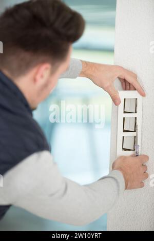 Elektriker in einheitlich montierten Steckdosen Stockfoto