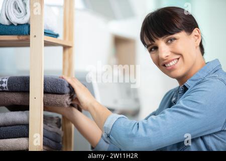 Glückliche Frau räumt die Handtücher auf Stockfoto