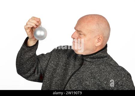 Reifer kaukasischer Mann mit silbernem Weihnachtsbaum-Ornament in grauer Pullover-Jacke - festliches saisonales Porträt mit Kopierraum Stockfoto