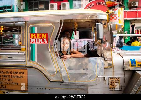 Ein hübsches, junges Filipino-Mädchen, das lächelt, saß auf einem Jeepney von Manila. Stockfoto