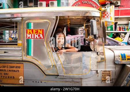 Ein hübsches, junges Filipino-Mädchen, das lächelt, saß auf einem Jeepney von Manila. Stockfoto