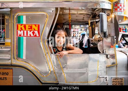 Ein hübsches, junges Filipino-Mädchen, das lächelt, saß auf einem Jeepney von Manila. Stockfoto