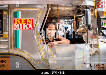 Ein hübsches, junges Filipino-Mädchen, das lächelt, saß auf einem Jeepney von Manila. Stockfoto