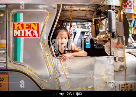 Ein hübsches, junges Filipino-Mädchen, das lächelt, saß auf einem Jeepney von Manila. Stockfoto