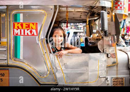 Ein hübsches, junges Filipino-Mädchen, das lächelt, saß auf einem Jeepney von Manila. Stockfoto