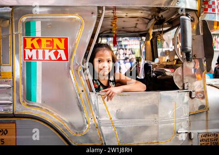 Ein hübsches, junges Filipino-Mädchen, das lächelt, saß auf einem Jeepney von Manila. Stockfoto