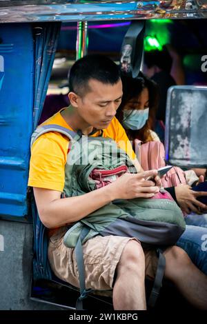 Ein philippinischer Mann blättert ein Handy, das auf einem Jeepney von Manila saß. Stockfoto