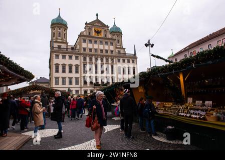 Augsburg, Deutschland-15. Dezember 2023: Auf dem Augsburger Weihnachtsmarkt spazieren die Menschen mit dem Rathaus im Hintergrund. Stockfoto