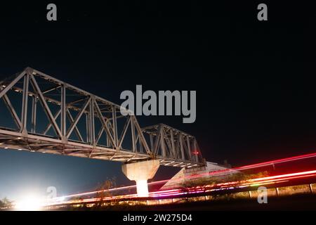 Halten Sie den urbanen Zauber einer Stadt bei Nacht mit diesem atemberaubenden Langzeitfoto einer Brücke in warmem Licht fest Stockfoto