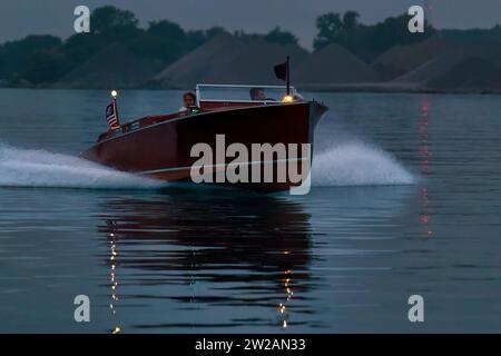 Zwei Personen, die in einem alten Schnellboot in der frühen Morgenröte fahren. Stockfoto