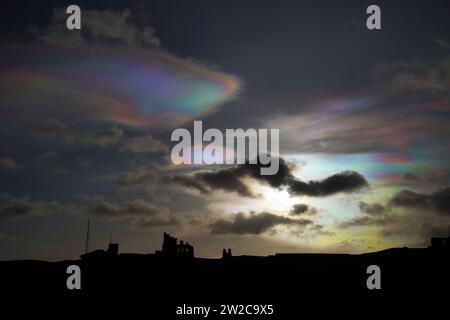 Seltene Nacreous Wolken, auch Regenbogenwolken genannt, bilden sich am Himmel über der Priory Tynemouth im Nordosten Englands. Die pastellfarbenen Wolken, die hoch in der Atmosphäre vorkommen, entstehen bei extrem niedrigen Temperaturen durch Sonnenlicht, das sich um Eiskristalle beugt. Bilddatum: Donnerstag, 21. Dezember 2023. Stockfoto