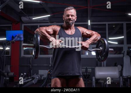 Bild eines starken Athleten, der eine Langhantel in einem Fitnessstudio hebt. Schulterpumpen. Fitness- und Bodybuilding-Konzept. Gemischte Medien Stockfoto