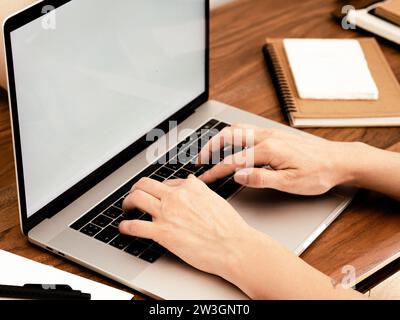 Nicht identifizierte Frau, die zu Hause an einem Laptop arbeitet. Person, die an einem Laptop arbeitet. Zu Hause arbeiten. Vorderansicht Stockfoto