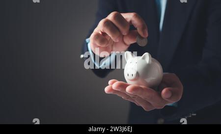 Geschäftsmann in Anzug hält Sparschwein. Finanzierungssparkonzept, Geldsparnis und Einlage für Investitionen, um Gewinn und Dividende zu erhalten, Planni Stockfoto