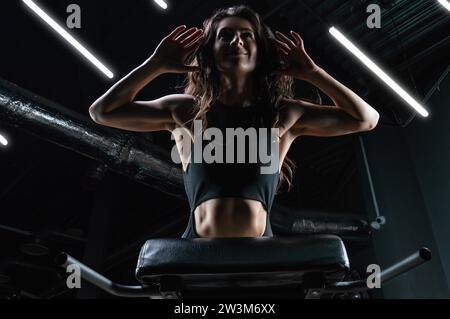 Charmante Brünette, die Hyperextension im Fitnessstudio macht. Drücken Sie die Pumpe. Fitness- und Bodybuilding-Konzept. Gemischte Medien Stockfoto
