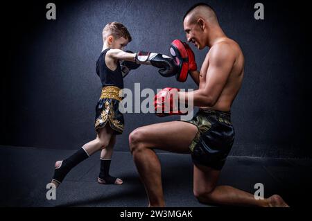 Kickboxtrainer trainiert den Jungen. Das Konzept von Familie, Sport, mma, muay thai. Gemischte Medien Stockfoto