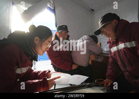 (231221) -- LINXIA, 21. Dezember 2023 (Xinhua) -- Mitglieder eines psychologischen Beratungsteams interpretieren den emotionalen Zustand der Kinder basierend auf ihrer Malarbeit an einem temporären Umzugsort im Dorf Yangwa im Jishishan County, Nordwestchinas Provinz Gansu, 21. Dezember 2023. Nach dem Erdbeben der Stärke 6,2 in der Provinz Gansu im Nordwesten Chinas sind insgesamt 28 Experten für psychische Gesundheit auf nationaler und provinzieller Ebene nach Gansu gekommen, um stationäre Patienten und deren Gefährten, die Familien der Opfer und die vom Erdbeben betroffenen Personen, einschließlich der Katastrophe, psychologische Beratung anzubieten Stockfoto