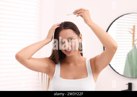 Schöne Frau, die drinnen Serum auf die Haare aufträgt Stockfoto