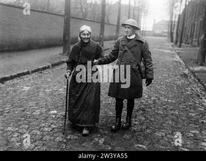 Offizielles Foto an der britischen Westfront, das einen Soldaten zeigt, der älteren Zivilisten hilft Stockfoto