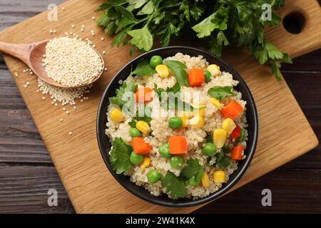 Leckerer Quinoa-Brei mit Gemüse in Schüssel auf Holztisch, flach gelegt Stockfoto