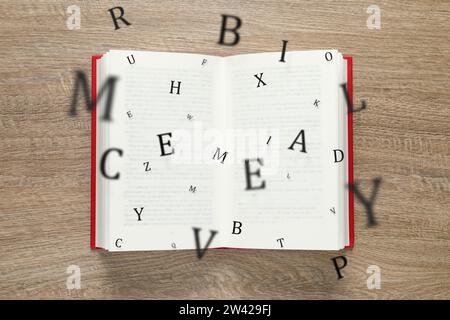 Offenes Buch mit Buchstaben, die auf hölzernem Hintergrund herausfliegen, Draufsicht Stockfoto
